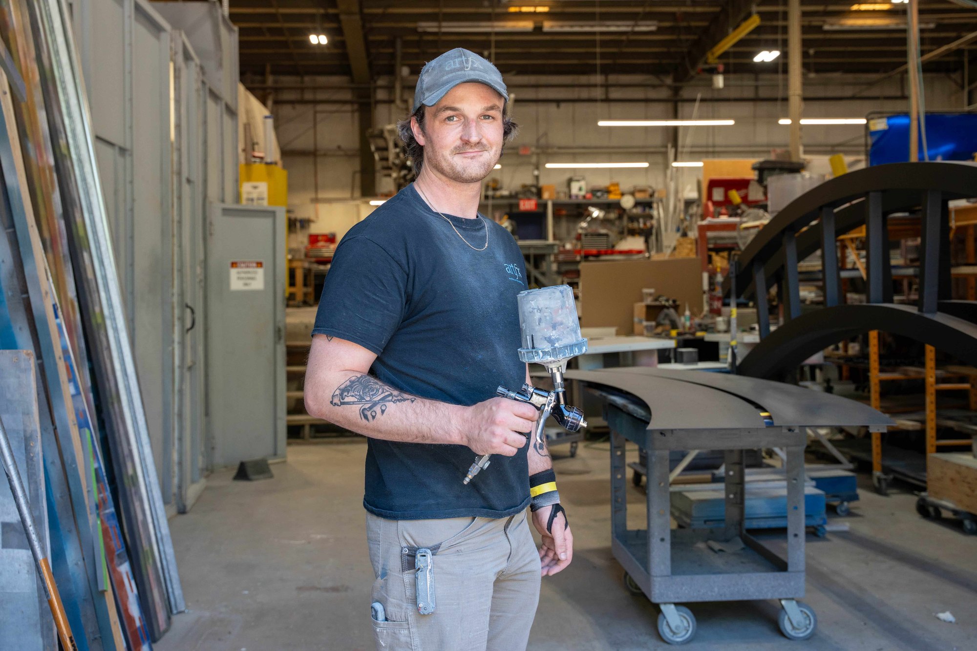 ARTfx spray painter holding a paint gun in the fabrication shop